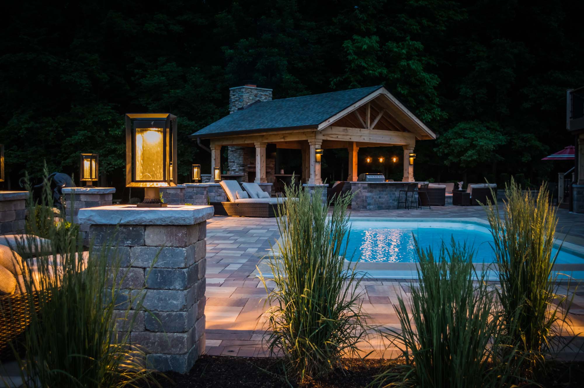 Outdoor living pool structure with fireplace and landscape lighting